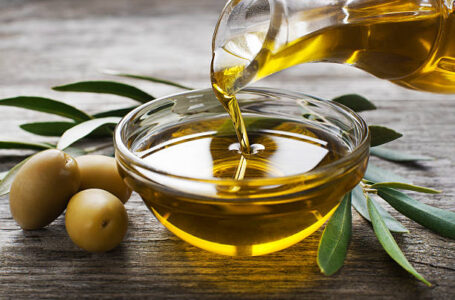 Bottle pouring virgin olive oil in a bowl close up